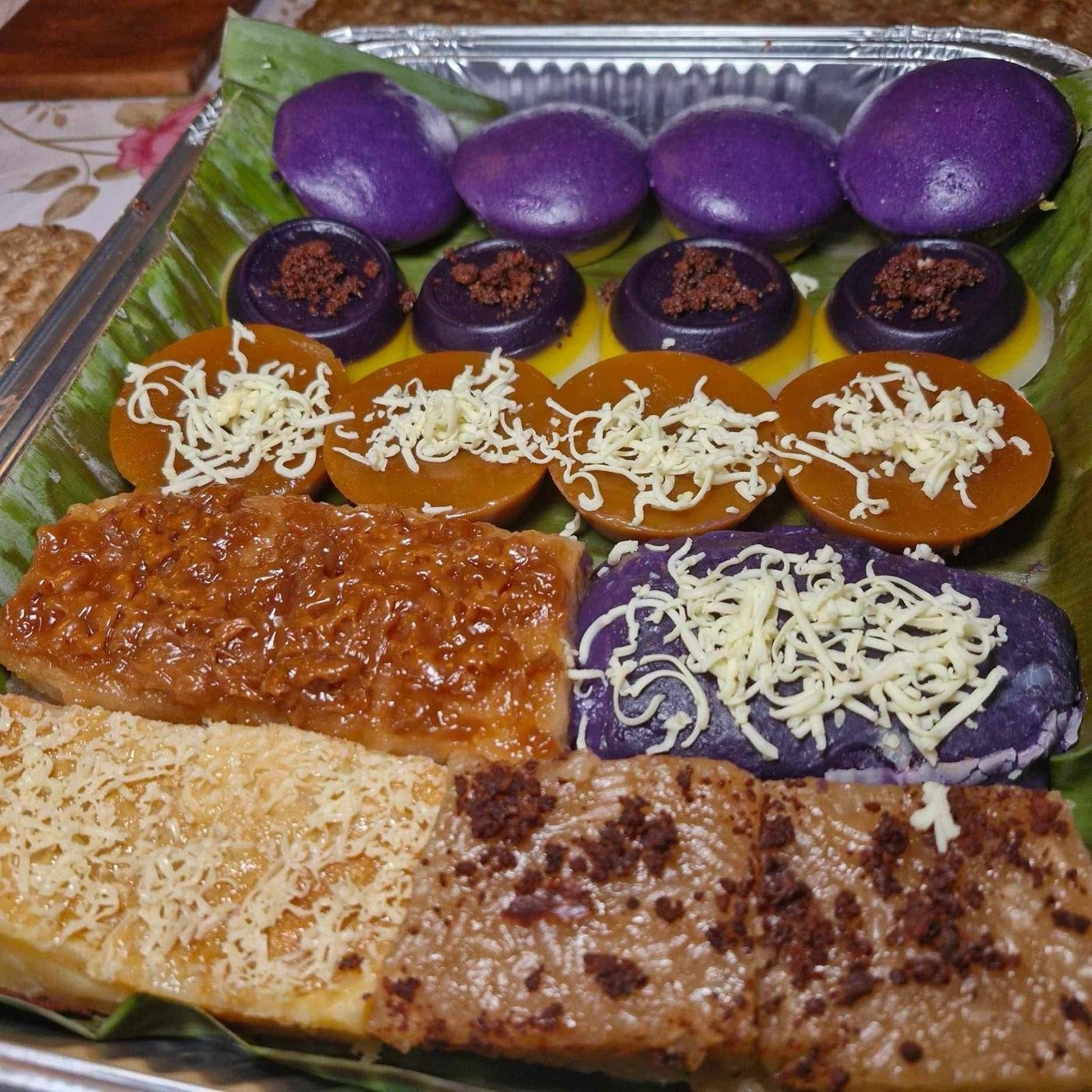 Assorted kakanin tray with ube halaya, biko, cassava cake, sapin-sapin, and puto ube